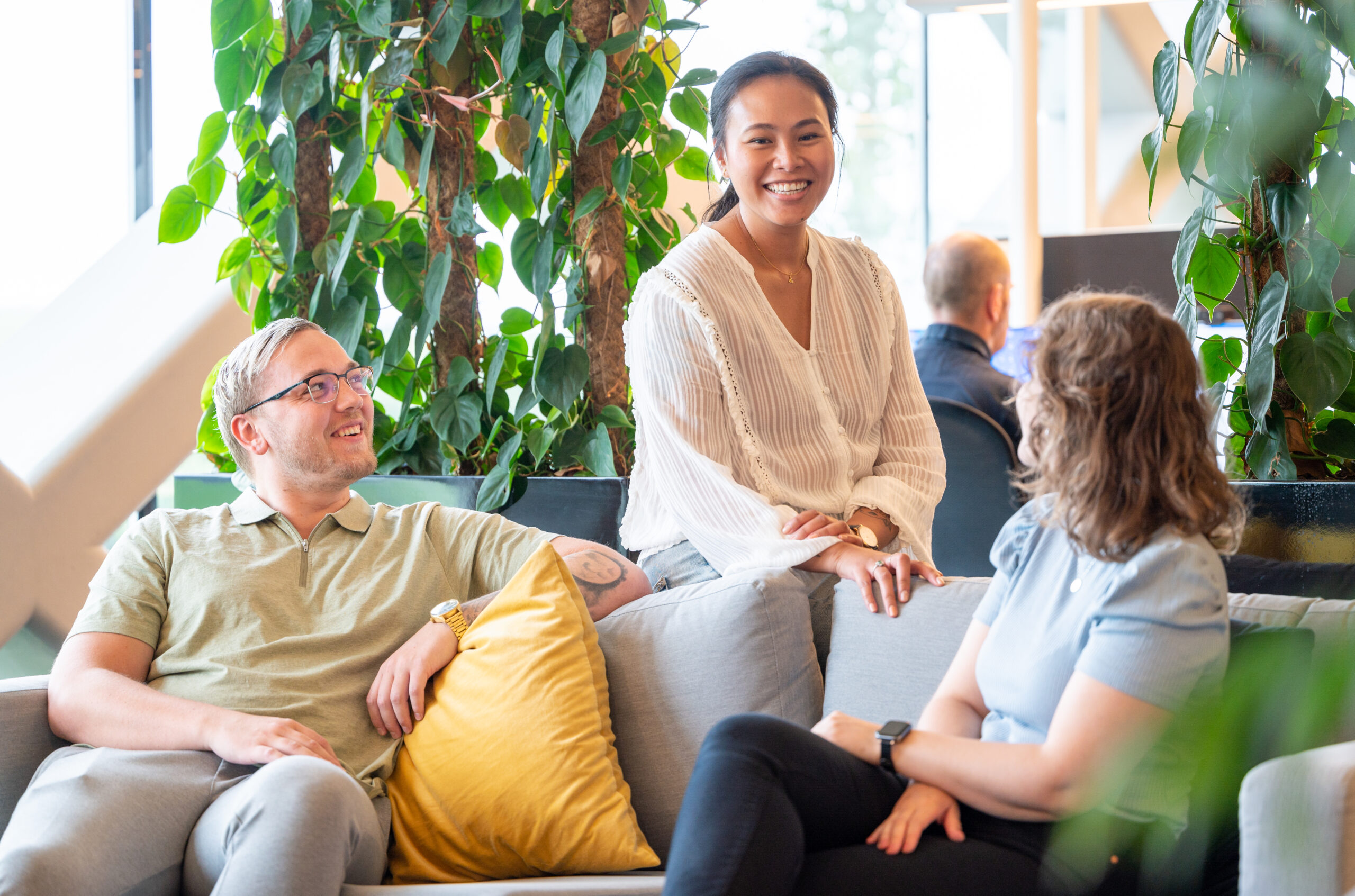 Tre IT-konsulenter sitter i en sofa og snakker. Foto.