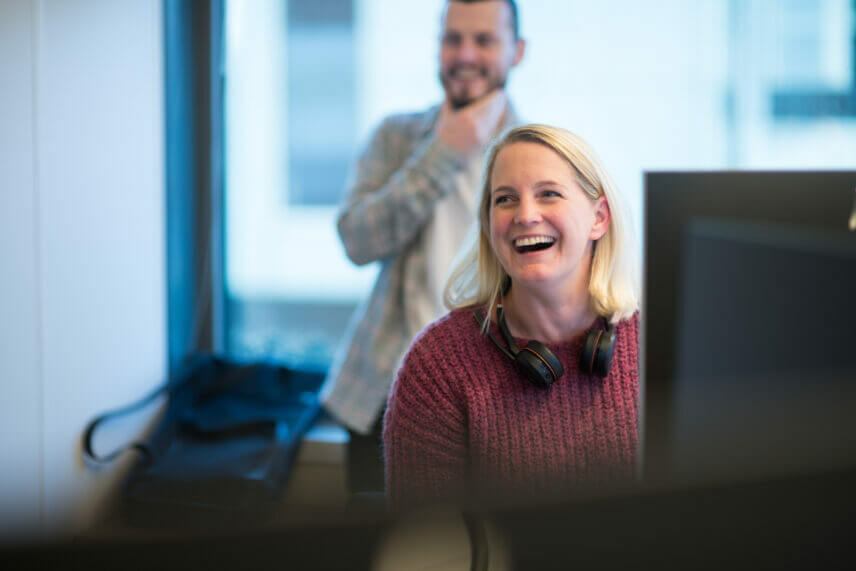 IT-konsulent som ler på arbeidsplassen. Foto.